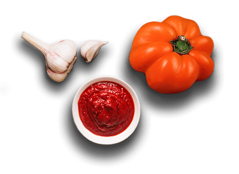 garlic and a tomato next to a pizza sauce - close up