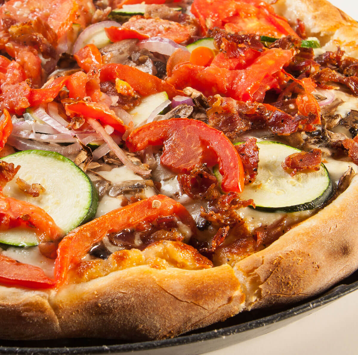 Pizza topped with fresh tomatoes, zucchini, red peppers and onions